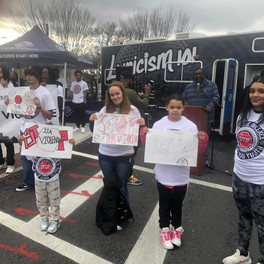 Group of people holding signs with text, BGCCA event in progress.