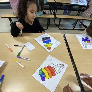 Young girl coloring a lightbulb on paper with rainbow colors. BGCCA