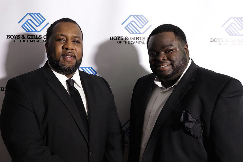 Two men smiling in front of a Boys & Girls Club backdrop BGCCA.