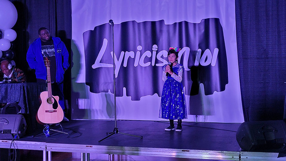 Young girl singing on stage with "Lyricism 101" background BGCCA 2022 Golf Tournament