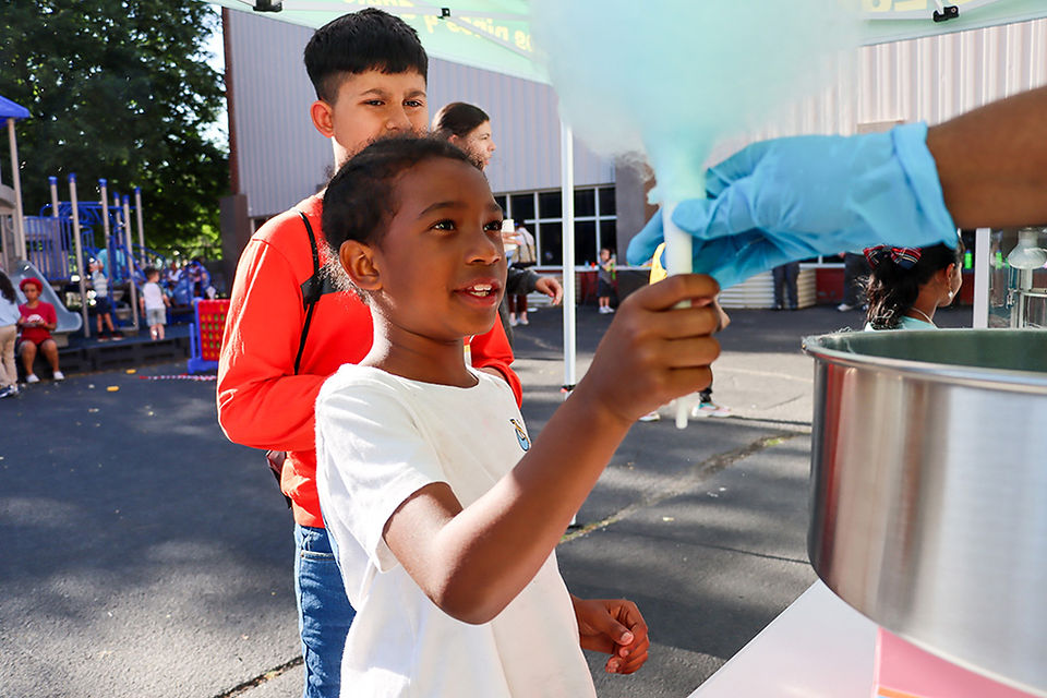 Boy gets cotton candy at an outdoor event, smiling. 2024-25 Kwanzaa.