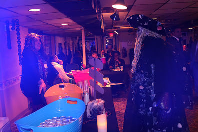 Person in costume at event with tables, BGCCA, and a blue bucket.