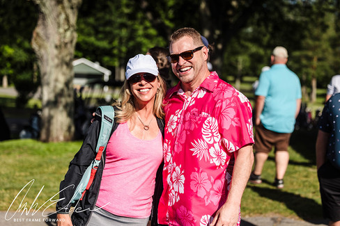 Smiling couple posing outdoors during the 2023 BGCCA Golf Tournament in sunlight.