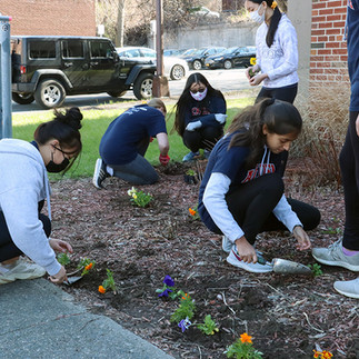 Group of students planting flowers, smiling, working together, spring day BGCCA.