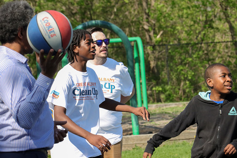 Teenager holding Cookies basketball with Clean Up shirt, group in park setting.