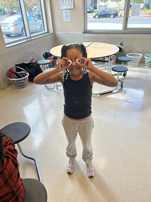 Young girl holding eyeballs over her eyes, smiling, wearing black tank top
