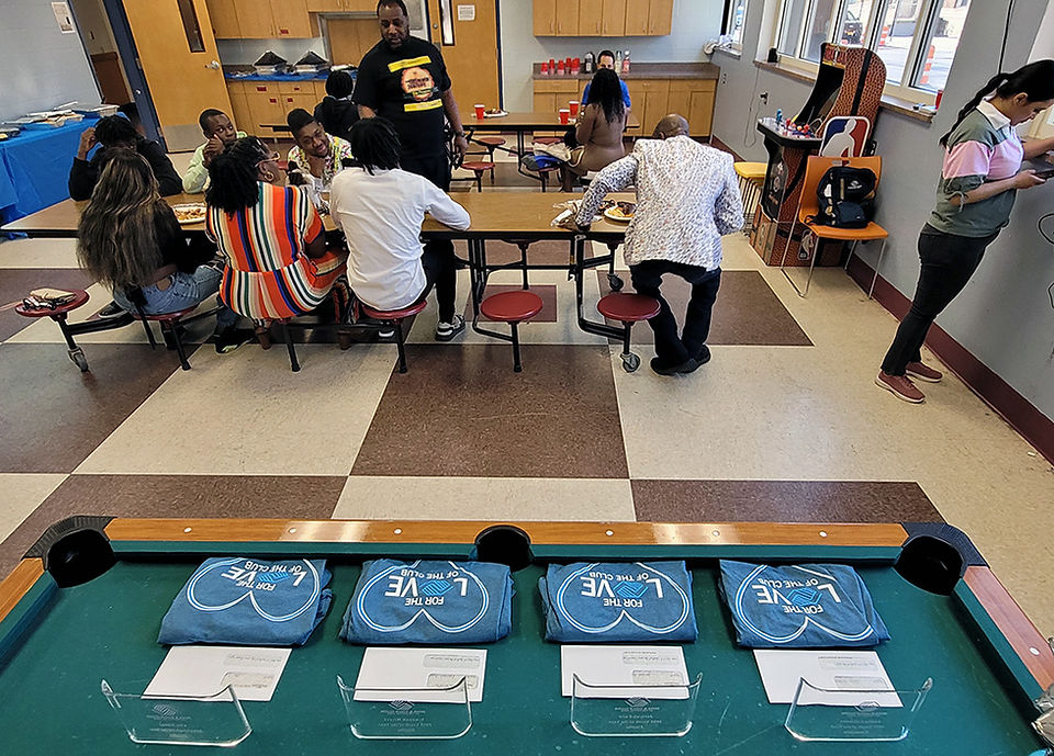 Group of people seated around tables with pool table and signs.