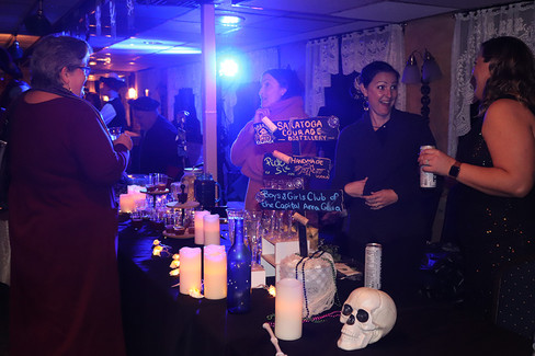 People near bar with drinks and sign for Capital Yacht Club Gala event.