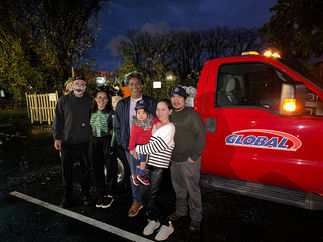 Group photo poses near a red Global truck with visible text, Halloween 2023.