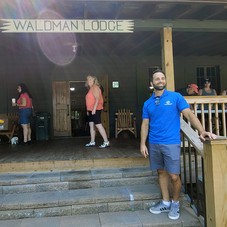 Man stands by Waldman Lodge entrance. People are in the background.