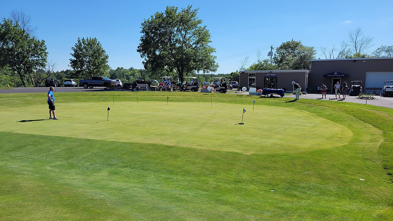 Green golf course with carts and flags on a sunny day. BGCCA