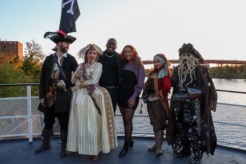 Group of people dressed as pirates posing for a photo on a boat.