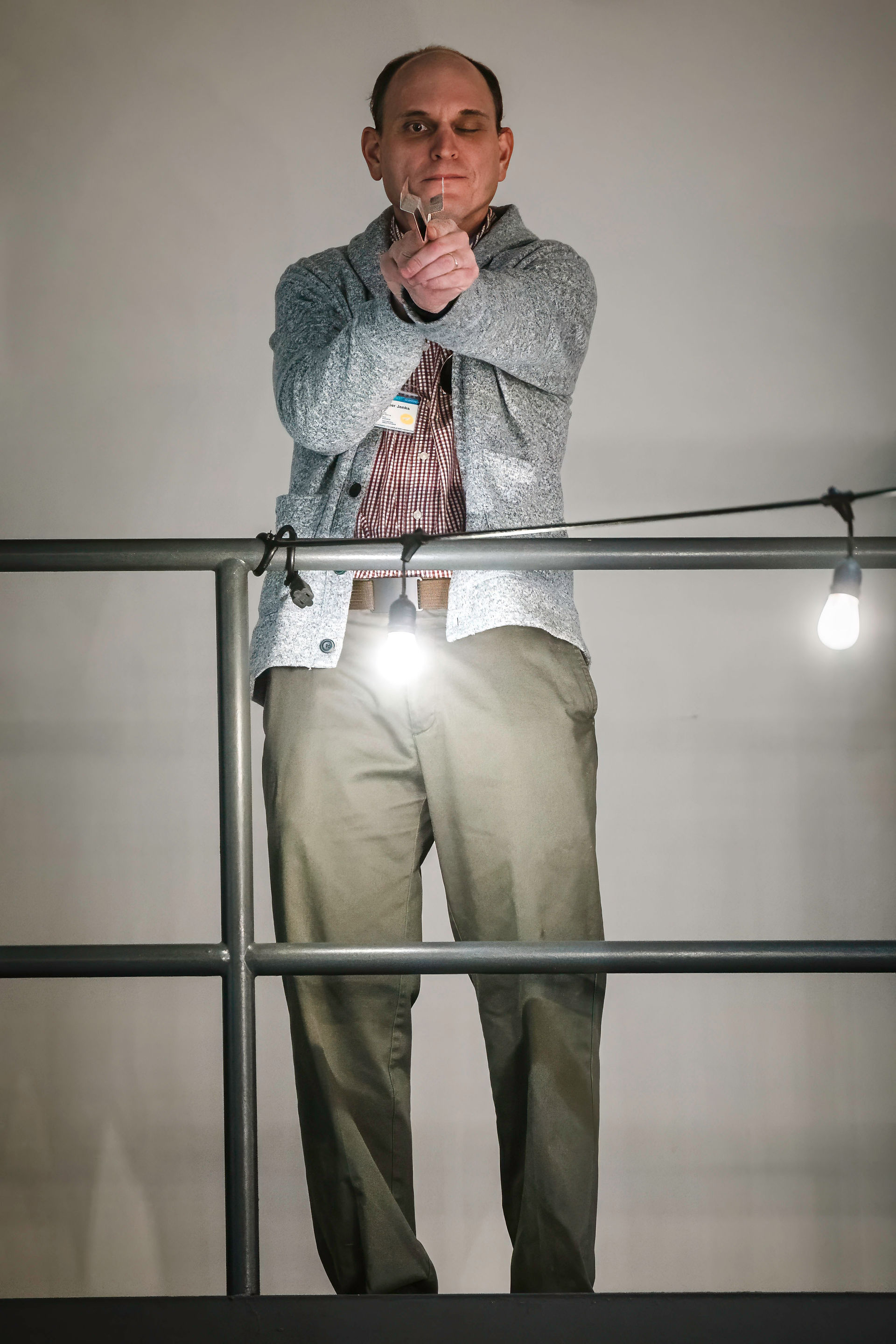 Man standing on a balcony, applauding, with string lights overhead.