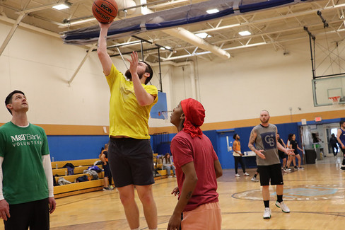 Man shoots basketball, others watch in indoor court setting BGCCA play.
