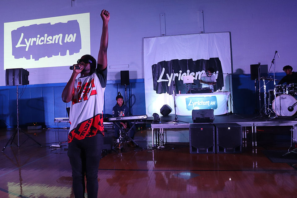 Man on stage with raised fist, Lyricism 101, performance with DJ BGCCA.