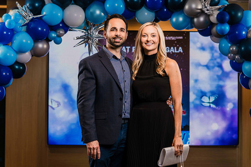 Couple poses in front of a gala backdrop with balloon arch, Great Futures Gala.