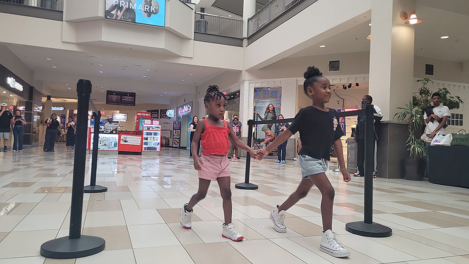 Two young girls holding hands walking in the shopping mall BGCCA.