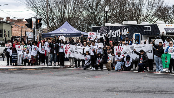 Group of people protesting with signs bearing various messages. Stop the Violence BGCCA