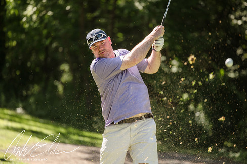 Golfer swings club during play, focused on action, 2023 Golf Tournament.