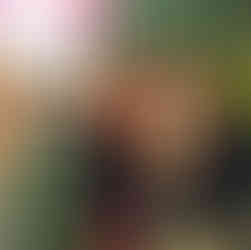 Four smiling girls posing together in a school classroom setting, smiling.