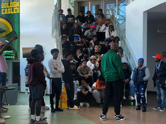 Group of students on steps listening to a speaker in front