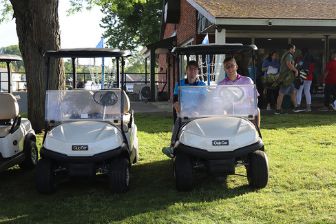 Two men in golf carts on a green grass at BGCCA. 2023 Golf Tournament