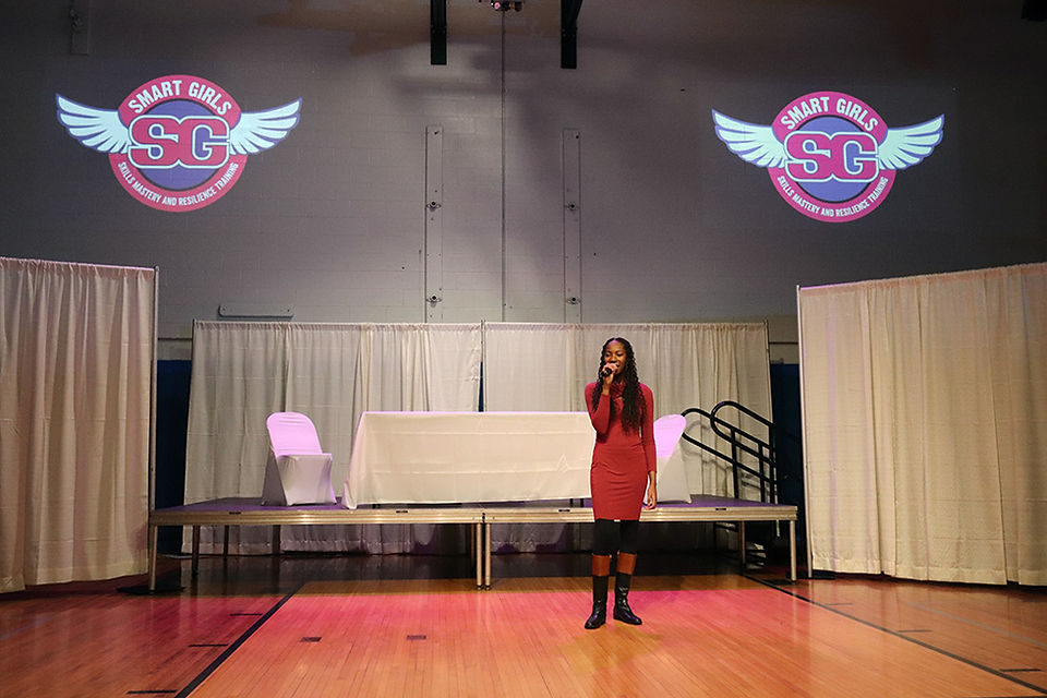 Woman speaking on stage with SMART GIRLS logo BGCCA 2024 Women's History Tea