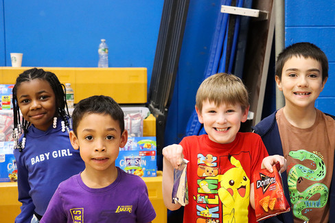 Two smiling children holding snacks with a water bottle in the background