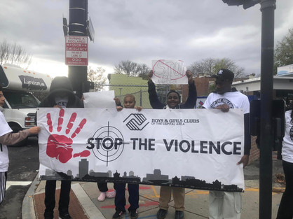 Children holding a banner that says Stop the Violence BGCCA in a group