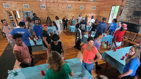 Group of people gathered around tables inside a wood-paneled room. BGCCA.