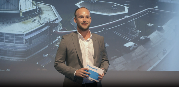 Felix Schlebusch im Business-Outfit mit DAIKIN Unterlagen vor Projektionshintergrund