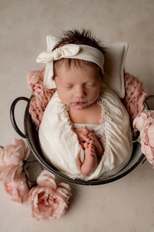 Neugeborenes Baby liegt in rustikaler Holzschale, dekoriert mit Moos und weißen Blüten, Studioaufnahme
