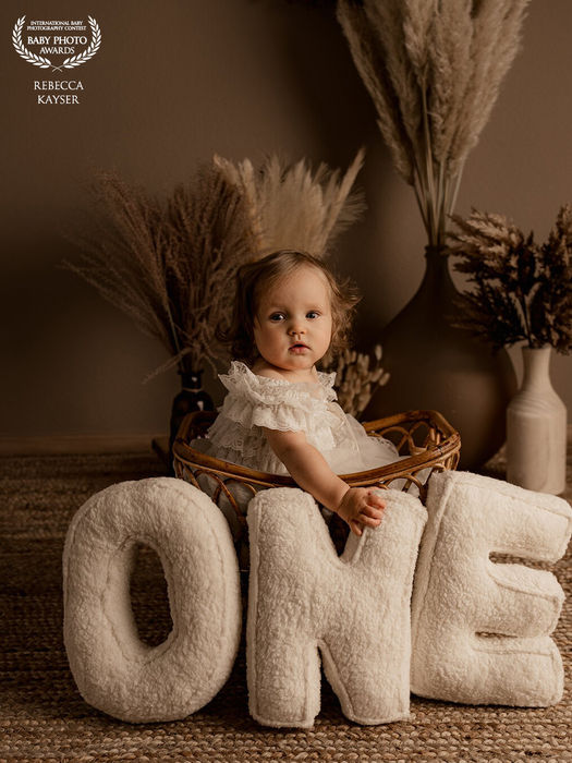 Kleine Mädchen in einem Weidenkorb mit den Buchstaben ONE davor