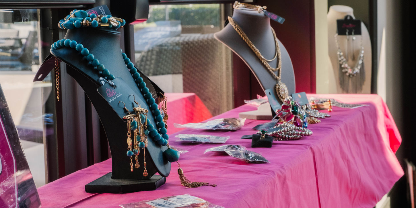 Jewelry display with necklaces, bracelets, and earrings on a pink table; various styles.