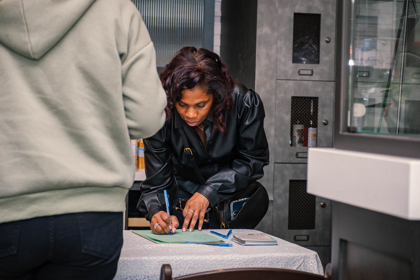 Woman signing a document at a table, with another person standing beside