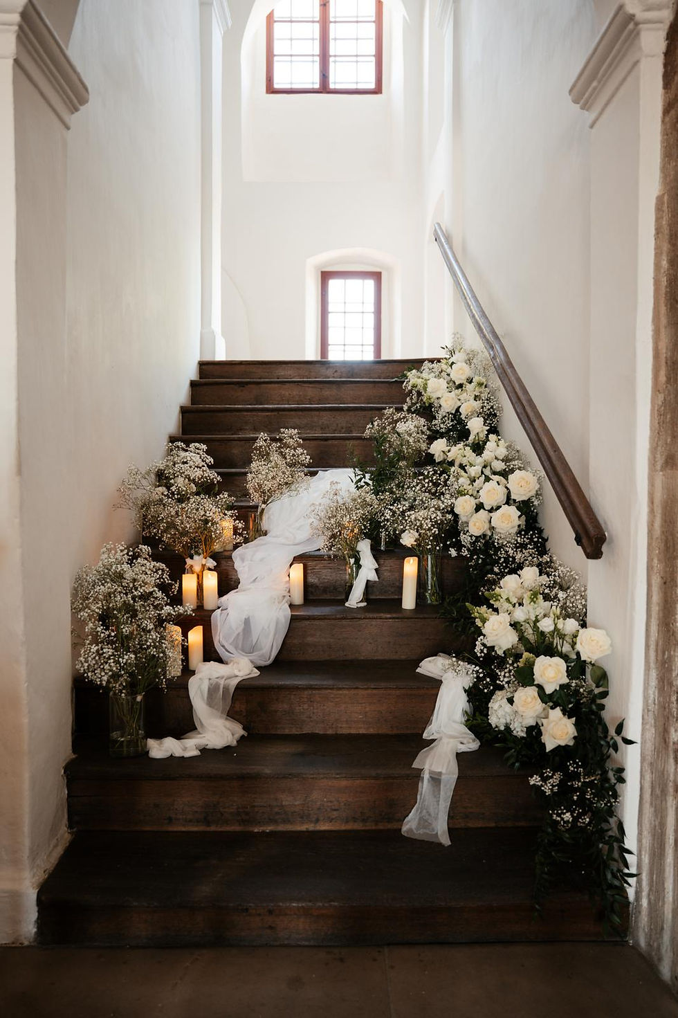 Elegante Hochzeitsdekoration auf Treppe mit weißen Rosen, Schleierkraut und Kerzen im Schloss Hemhofen mit Dekorelli 