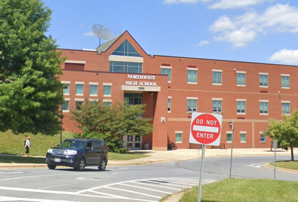 Red-brick school building labeled "Northwest High School" with a "Do Not Enter" sign. A black SUV on the road, trees and blue sky.