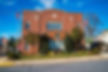 Brick town hall with flags on either side, trees in front, blue sky backdrop.