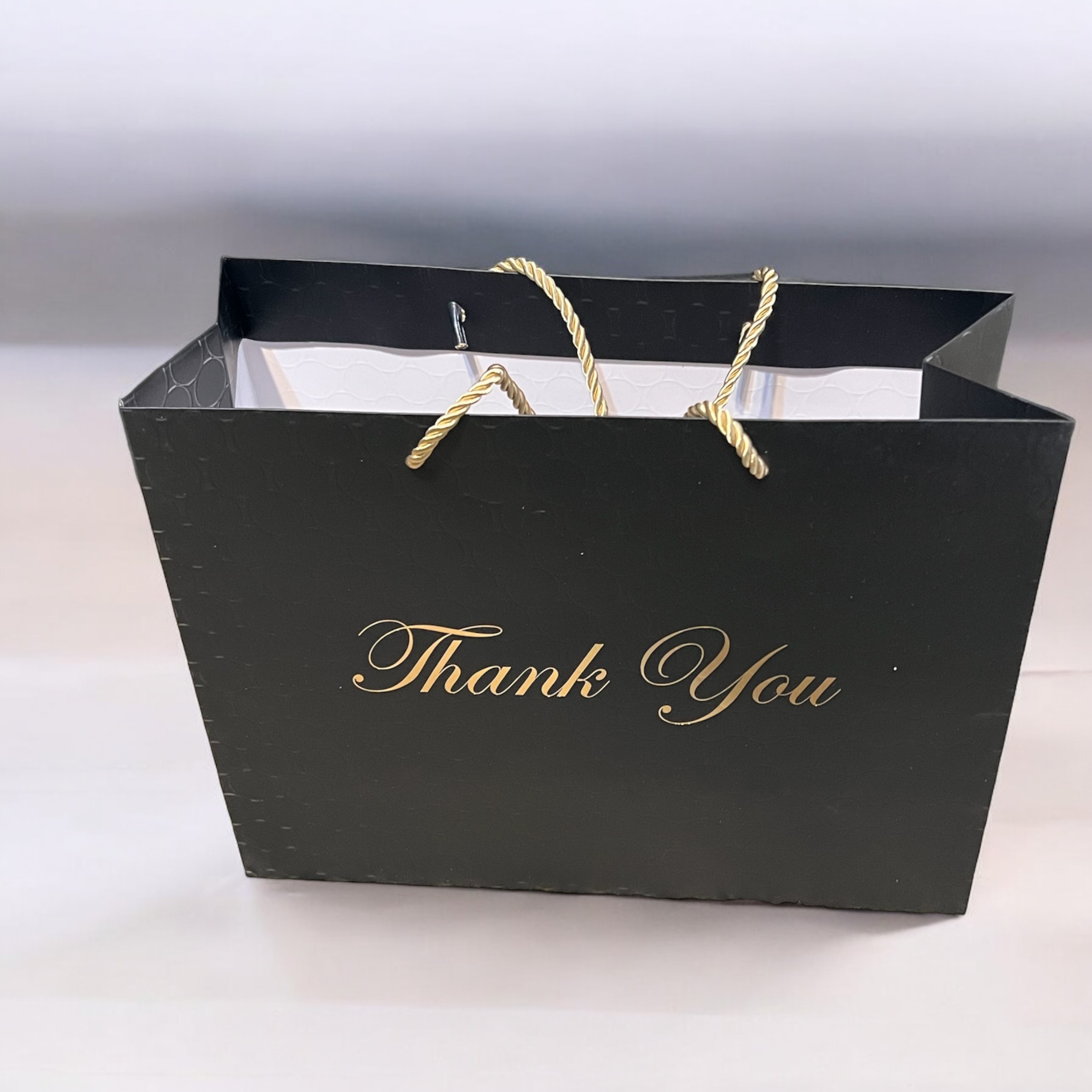 Black thank-you presentation bag with gold lettering and handles.