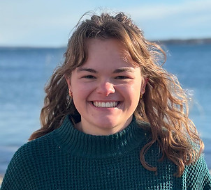 Young Woman wth curly light brown hir and teal sweater.