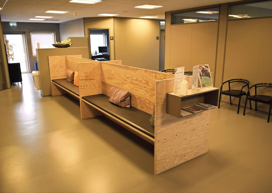 Venteområde med træbænke og behandlingsrumskorridor