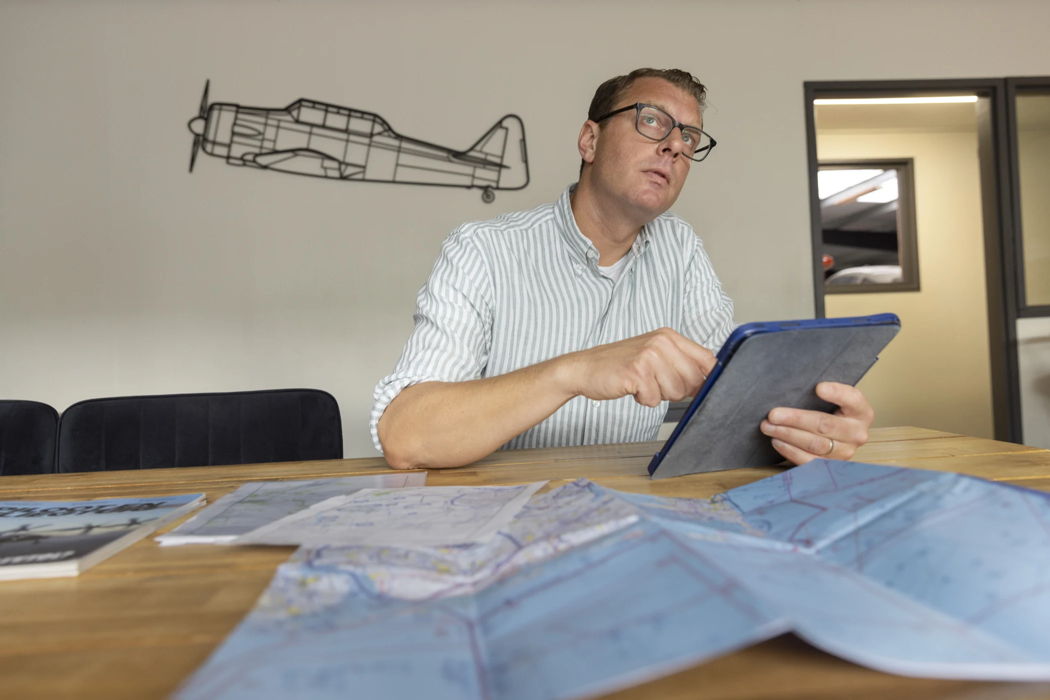 Bart van den Tol aan tafel met tablet en luchtvaartkaart