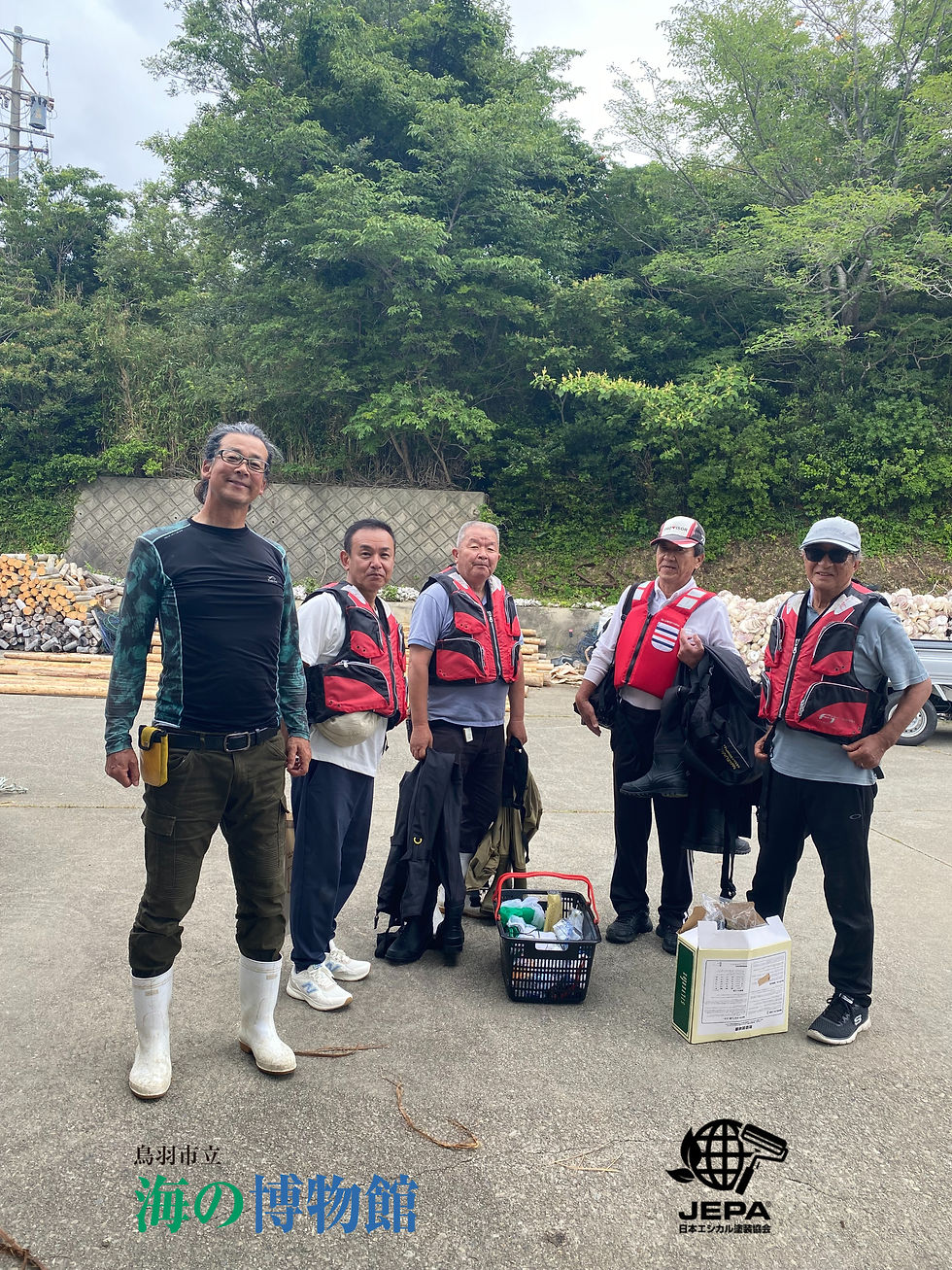 森林を背に、赤いライフベストを着た5人の男性が屋外で集合。作業道具や箱が足元にあり、和やかな表情。