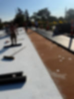Workers installing new white and brown commercial roof under clear blue sky.