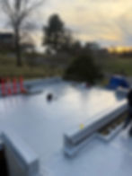 New flat commercial roof installation with tools and materials at dusk.