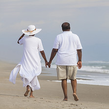 Couple holding hands while walking on the beach