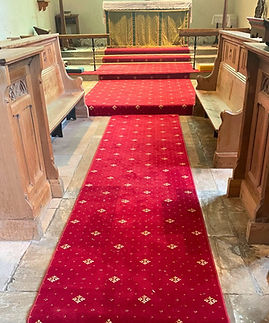 A red carpet with white flower embroidery design that has been installed in a chuch