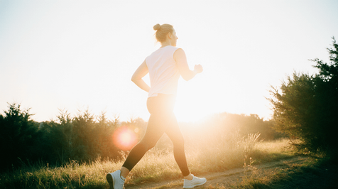 Vrouw wandelt energiek in de natuur bij zonsopgang, als visuele metafoor voor de effecten van alpha lipon zuur op energie en bloedsuikerspiegel.