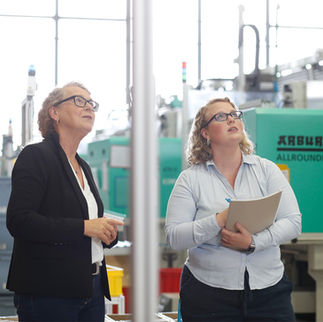 Zwei Frauen begutachten Maschinen in einer Produktionshalle.