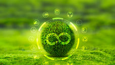 Grüne Kugel mit Unendlichkeitssymbol aus Moos, umgeben von kreisförmigen Icons zu Nachhaltigkeit und Umwelt, vor unscharfem grünen Hintergrund.